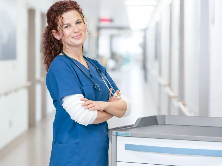 Nurse in blue scrubs standing beside a ZARGES medical cart in a hospital corridor