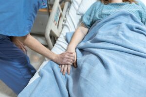 Nurse holding a patient's hand at the bedside